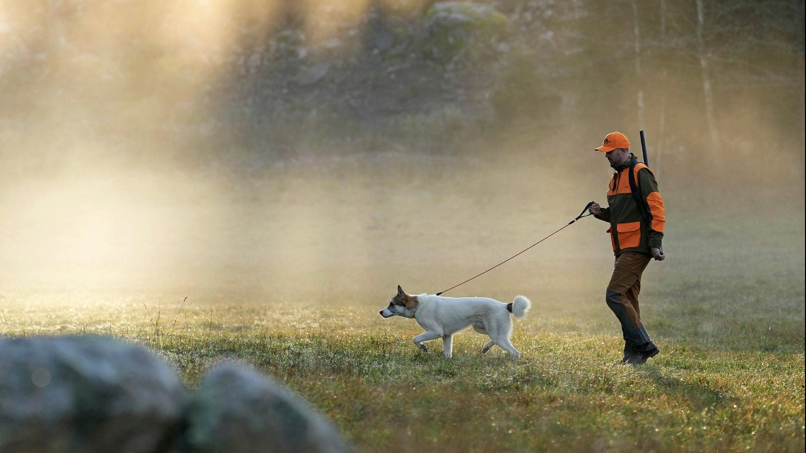 Jägare med Blaser gevär på ryggen tillsammans med jakthund i skogsmiljö